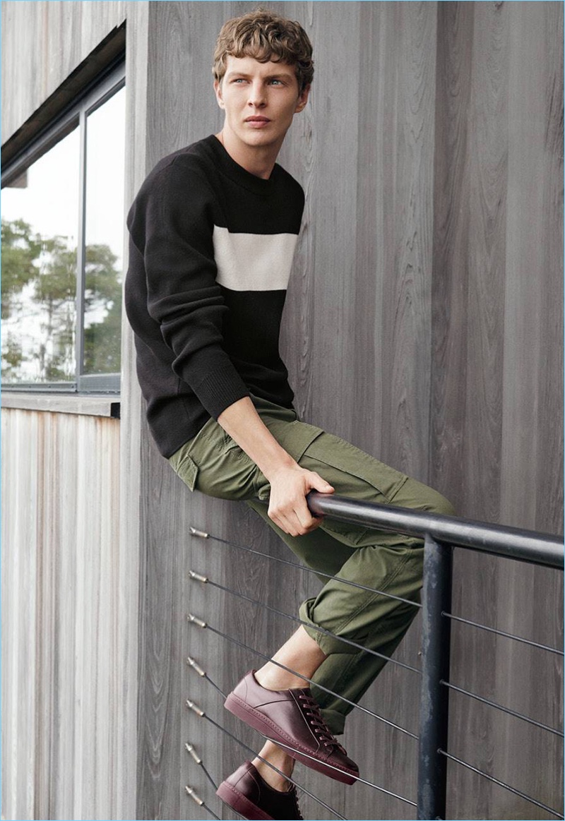 Embracing off-duty style, Tim Schuhmacher models a fine-knit sweater, cargo pants, and sneakers.