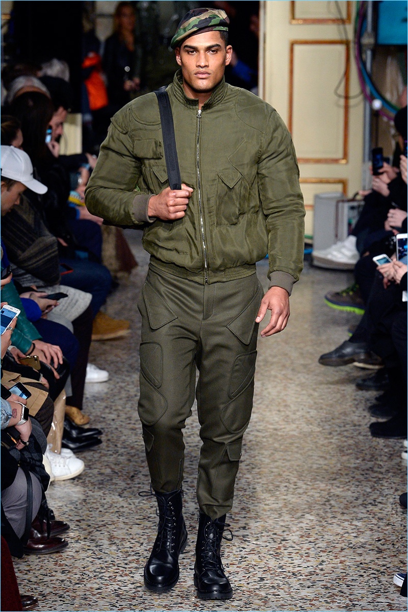 Rob Evans wears an army green bomber jacket and detailed pants from Moschino's fall-winter 2017 men's collection.