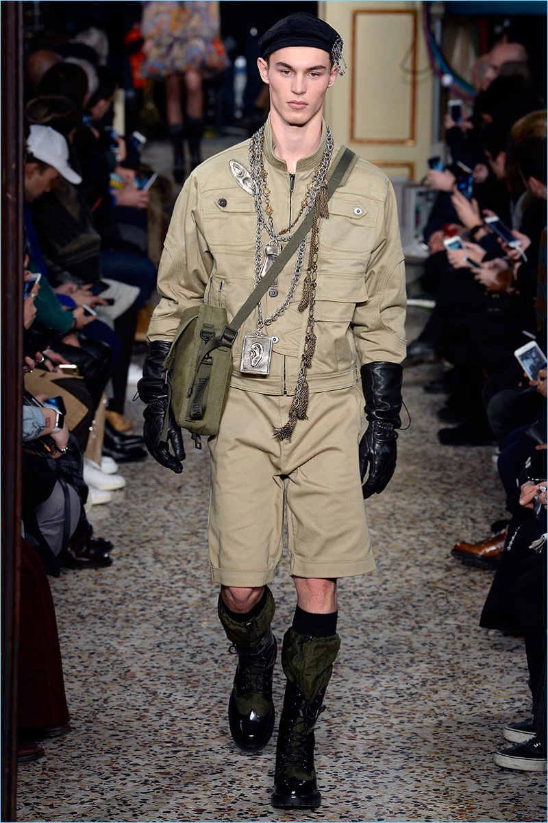 Kit Butler dons a khaki military inspired ensemble from Moschino's fall-winter 2017 men's collection.