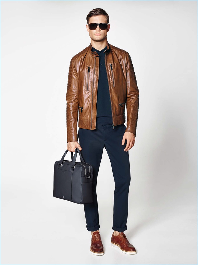 Porsche Design taps into moto style with a must-have motocross jacket in brown leather. The luxurious piece complements a navy polo shirt, pants, and leather lace-up shoes.