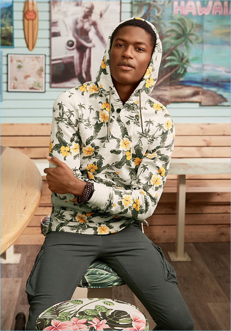 Embracing a tropical flair, Hamid Onifade wears LE 31's Fiji trip floral print hoodie with cargo joggers, and various bracelets.