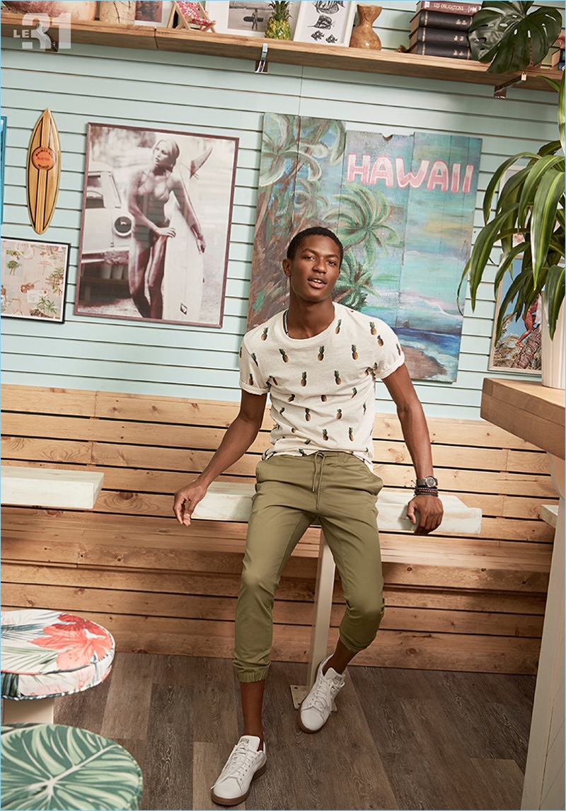 Model Hamid Onifade charms in a pineapple print t-shirt and joggers by LE 31. Hamid also sports Adidas Stan Smith sneakers.