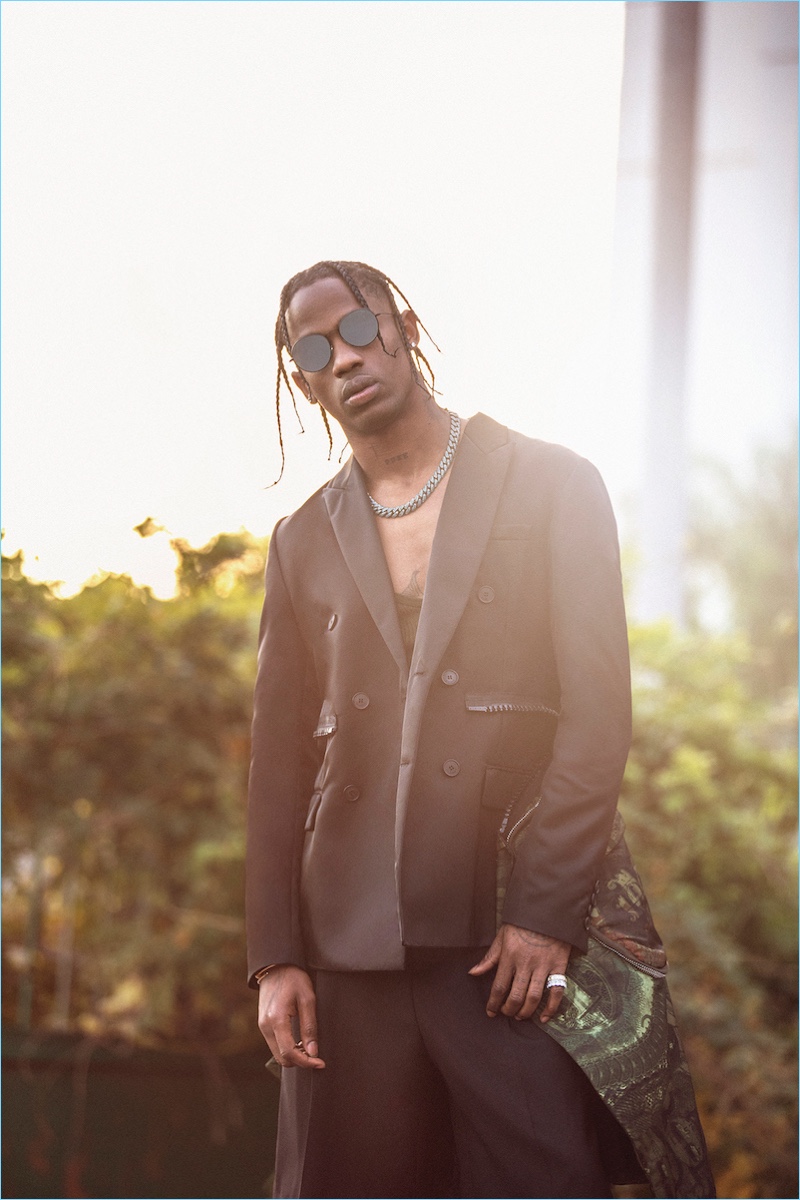 Travis Scott rocks a double-breasted jacket, tank, and shorts by Givenchy with RetroSuperFuture sunglasses.