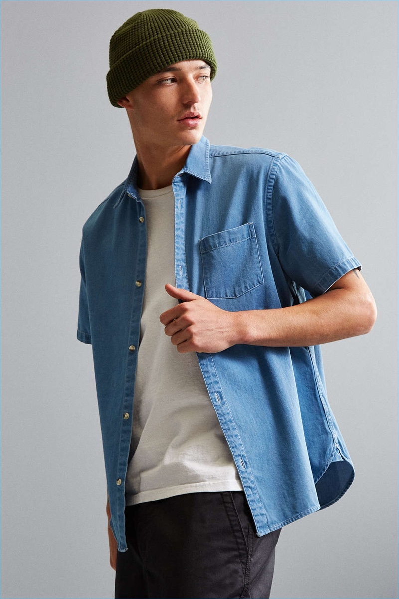 Versatile short sleeve button-down shirt from Urban Outfitters in classic cotton denim. Cut in a standard fit with a pointed collar, full-length front button closure and rounded hem. Finished with a front patch pocket.