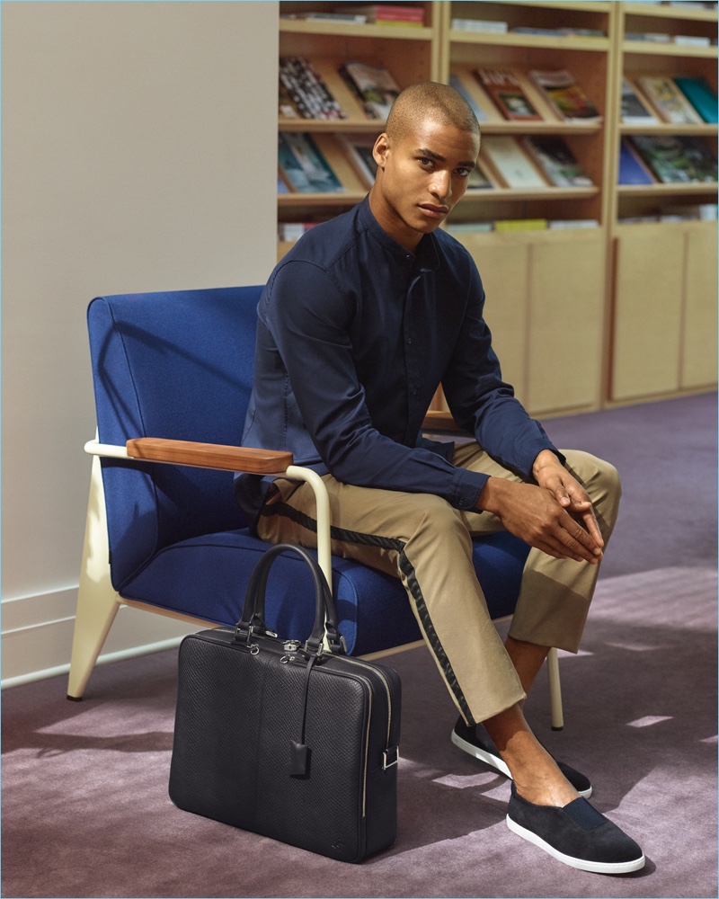 Model Malik Lindo wears WANT Les Essentiels' suede shoes, which complement the brand's leather briefcase.