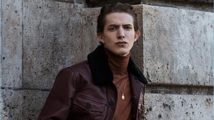 Model Xavier Buestel wears a Kenzo leather jacket with a Berluti turtleneck. The top model also rocks jeans, a leather belt, and necklace by Paul Smith.