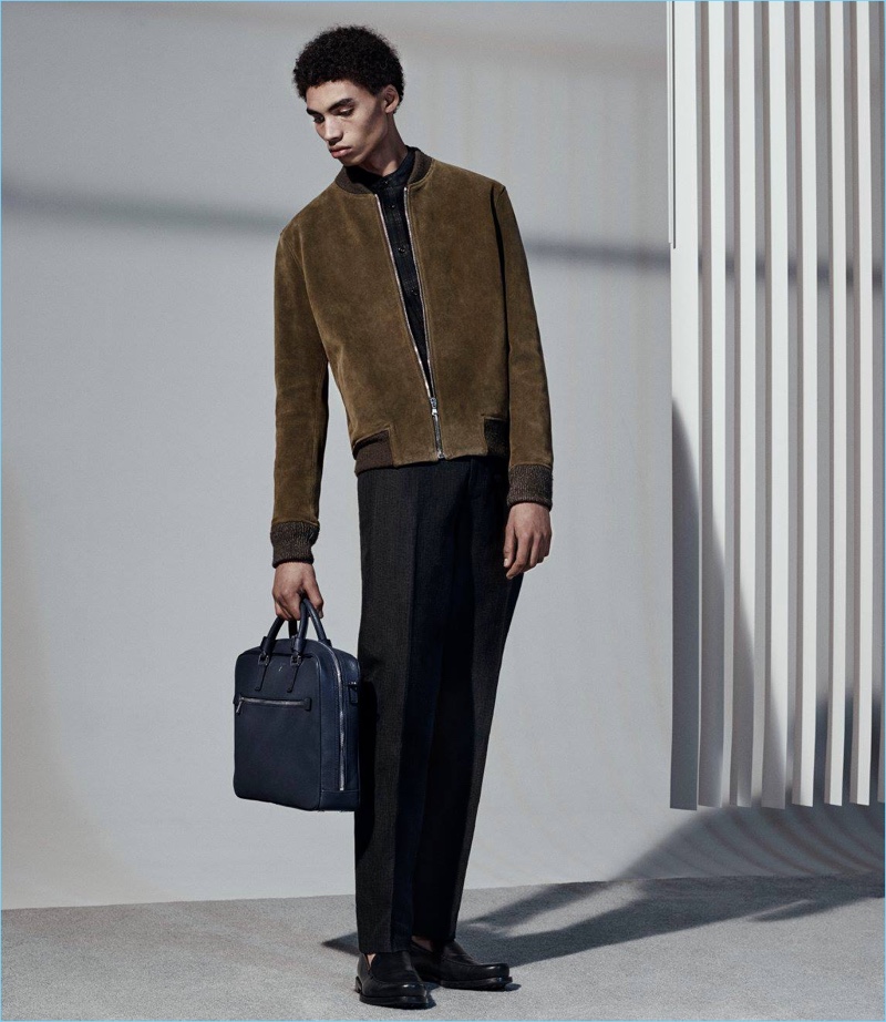 Starring in Barneys' latest lookbook, Sol Goss wears a Simon Miller suede bomber jacket with a Helbers shirt, John Varvatos trousers, Tod's penny loafers, and a Serapian double-zip briefcase.