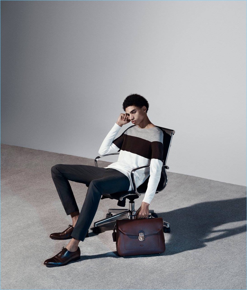 Tapping into smart casual style, Sol Goss sports Tomorrowland slim trousers with a Helbers sweater, Crockett & Jones leather shoes, and a Boldrini Selleria top-handle briefcase.