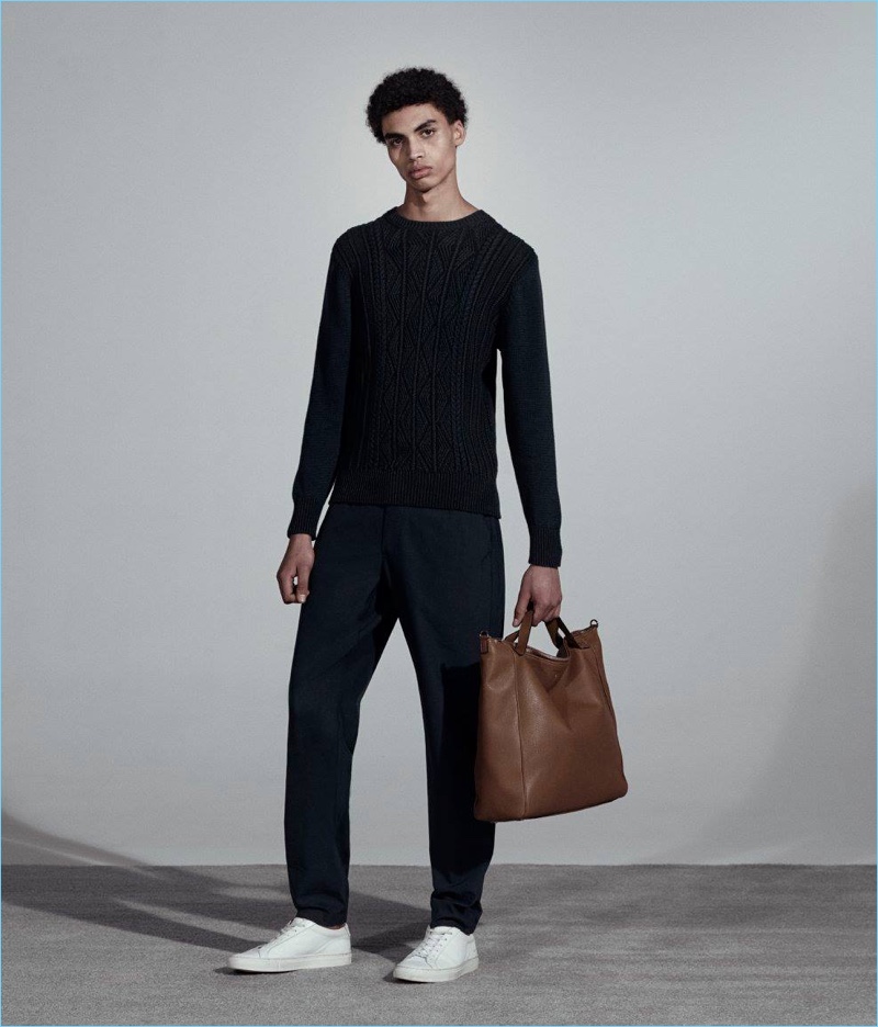 Going for a dark ensemble, Sol Goss wears an Inis Meain sweater with Incotex joggers and Common Projects sneakers. Sol also holds a Serapian top-zip tote bag.