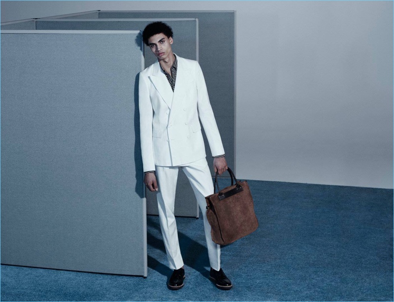 Embracing summer white, Sol Goss wears a Dries Van Noten double-breasted suit with a Barena Venezia striped polo shirt. Sol accessorizes with a Felisi open-top tote bag and Common Projects wedge-sole derbys. 