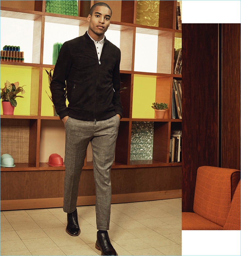 Malik Lindo embraces smart style with a bomber jacket, polo, and trousers by Ted Baker. Malik's look is complete with a pair of John Varvatos Star USA Chukka boots.