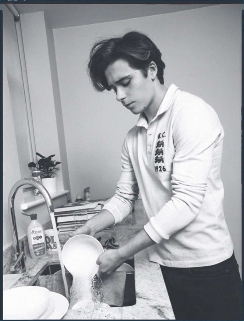 Washing dishes, Brooklyn Beckham sports a long-sleeve Kent & Curwen polo.