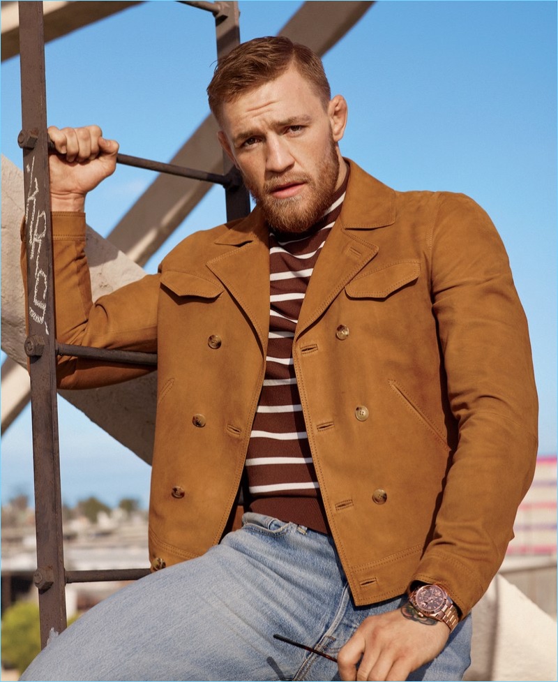 Appearing in a photo shoot for GQ Style, Conor McGregor dons a Boglioli suede jacket with a Neil Barrett t-shirt. McGregor also wears Levi's jeans and a Rolex watch.