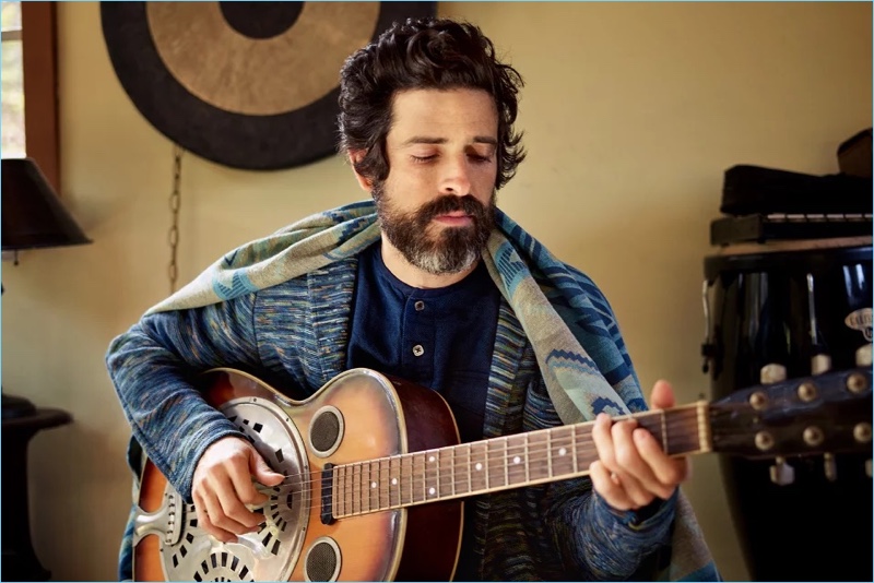 Playing the guitar, Devendra Banhart wears a Missoni knitted blazer with a collarless Blue Blue Japan shirt and Faherty jacquard blanket.