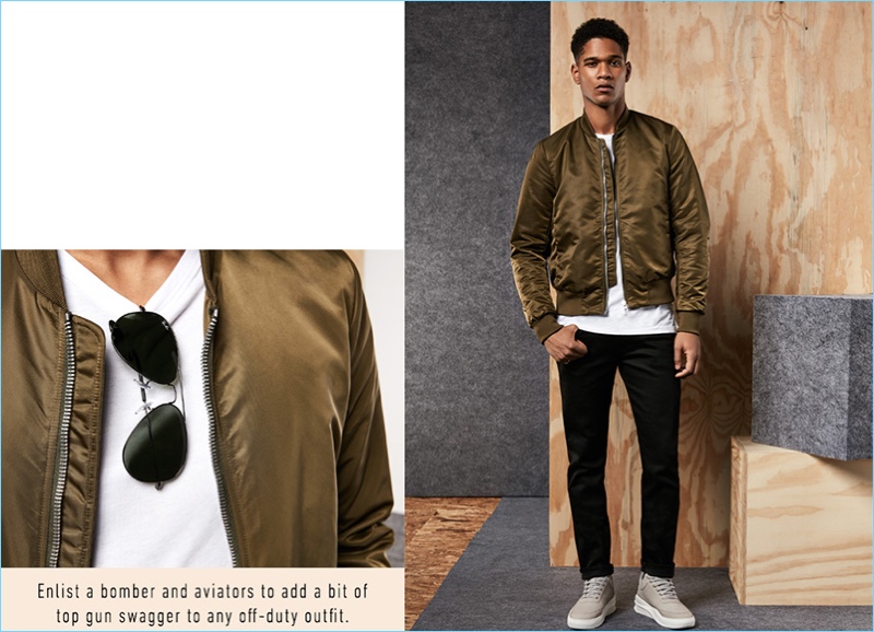 Embracing military style, Kadeem Fisher sports a PS by Paul Smith bomber jacket, Baldwin Denim jeans, a Vince shirt, and Ray-Ban aviator sunglasses.