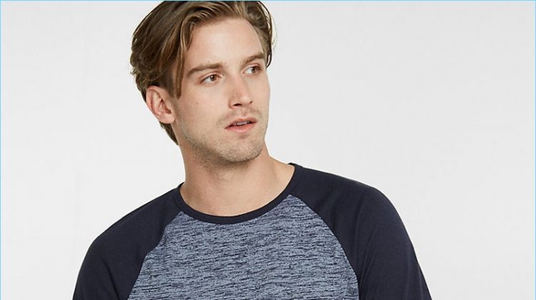 RJ King sports a heathered baseball tee from Express with distressed denim jeans and a plaid shirt.
