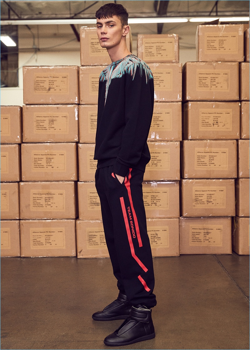 Embracing a black look, Simon Kotyk sports a Marcelo Burlon sweatshirt and sweatpants with Maison Margiela sneakers.