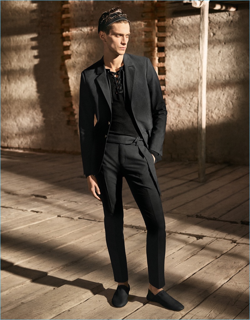 Dressed in head to toe black, Matthew Bell dons a blazer, trim trousers, and a lace-up top by H&M Studio.