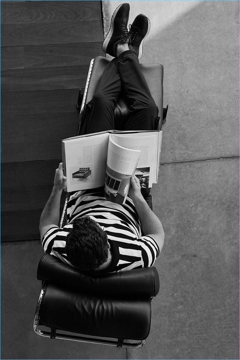 Reading a book, Justice Joslin wears a striped polo, cargo trousers, and sneakers from Massimo Dutti's limited edition Soft Collection.