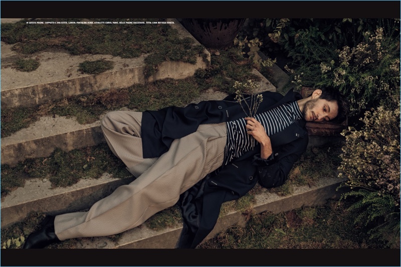 Relaxing, Pierre Niney wears a trench coat and striped turtleneck by Lanvin with oversized Fendi trousers.