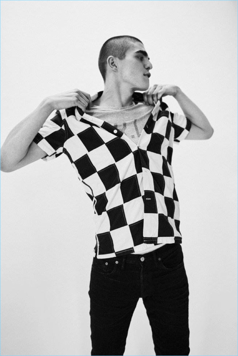 Model Diego Villarreal rocks a checkerboard print short-sleeve shirt, logo t-shirt, and black jeans from RRL.