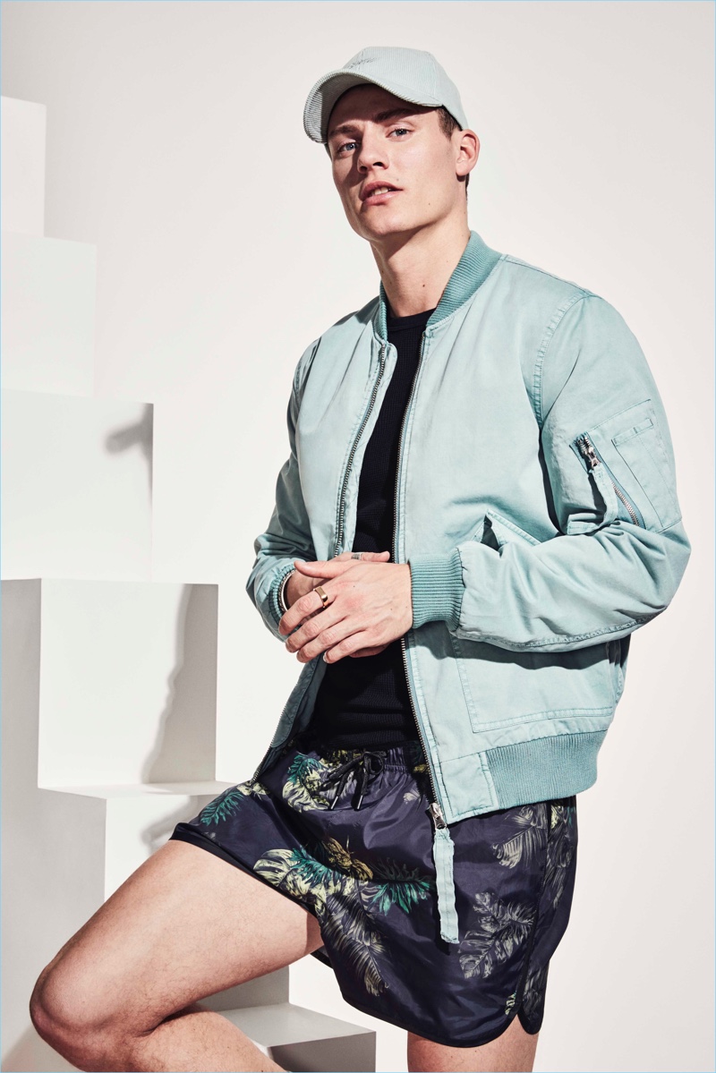 Model Mikkel Jensen sports a teal bomber jacket and swim shorts from River Island's high summer 2017 collection.