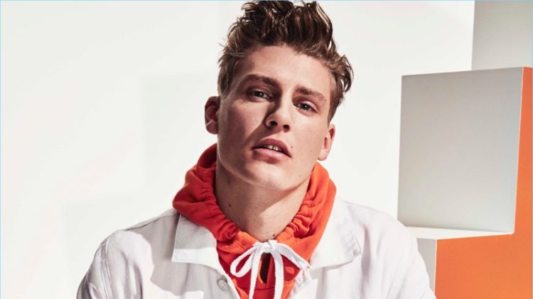 A colorful vision, Mikkel Jensen wears an orange hoodie with a white denim jacket and swim shorts by River Island.