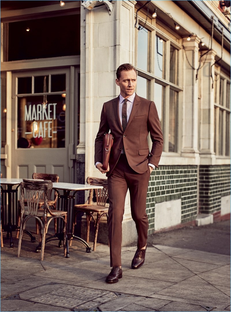 Heading out in London with GQ, Tom Hiddleston wears a brown Gucci made to order suit with a shirt and tie by the Italian label. Hiddleston also sports Church's shoes with a leather Louis Vuitton briefcase.