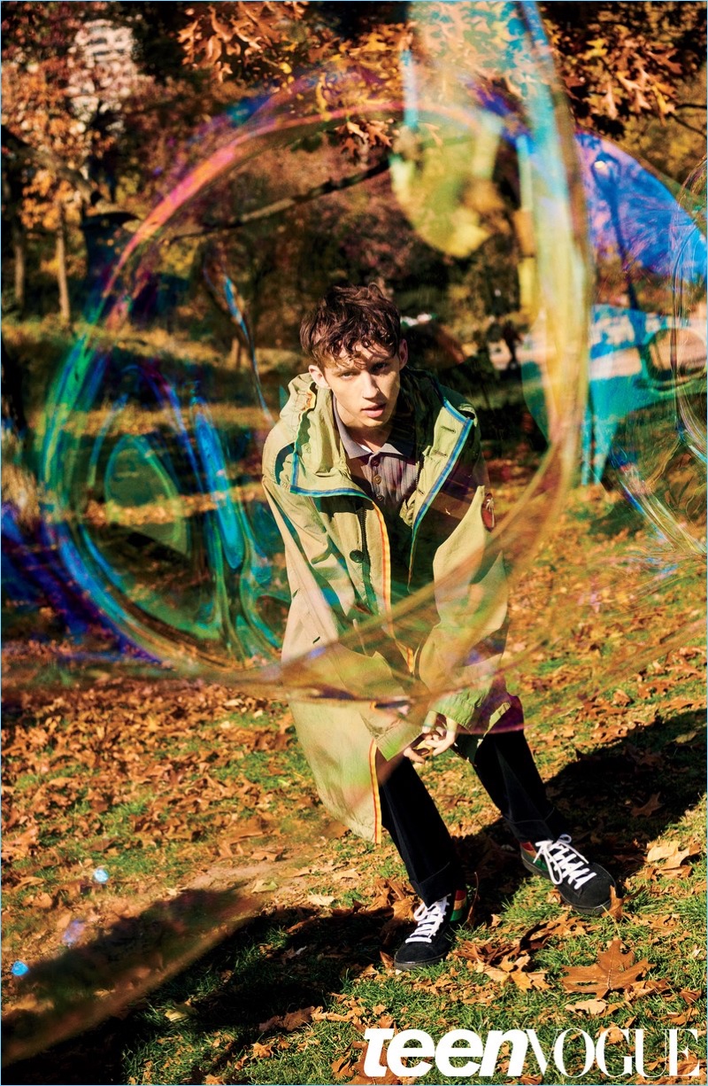 Playing with bubbles, Troye Sivan sports a Marc Jacobs parka and shoes. Sivan also wears a Valentino shirt.