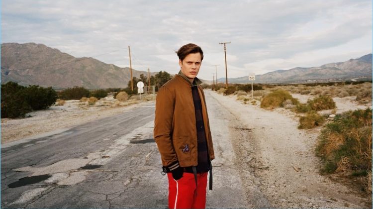 Bill Skarsgård wears a Lanvin bomber jacket with a sweater by The Soloist. Skarsgård also wears a Kent & Curwen shirt with Gucci trousers.