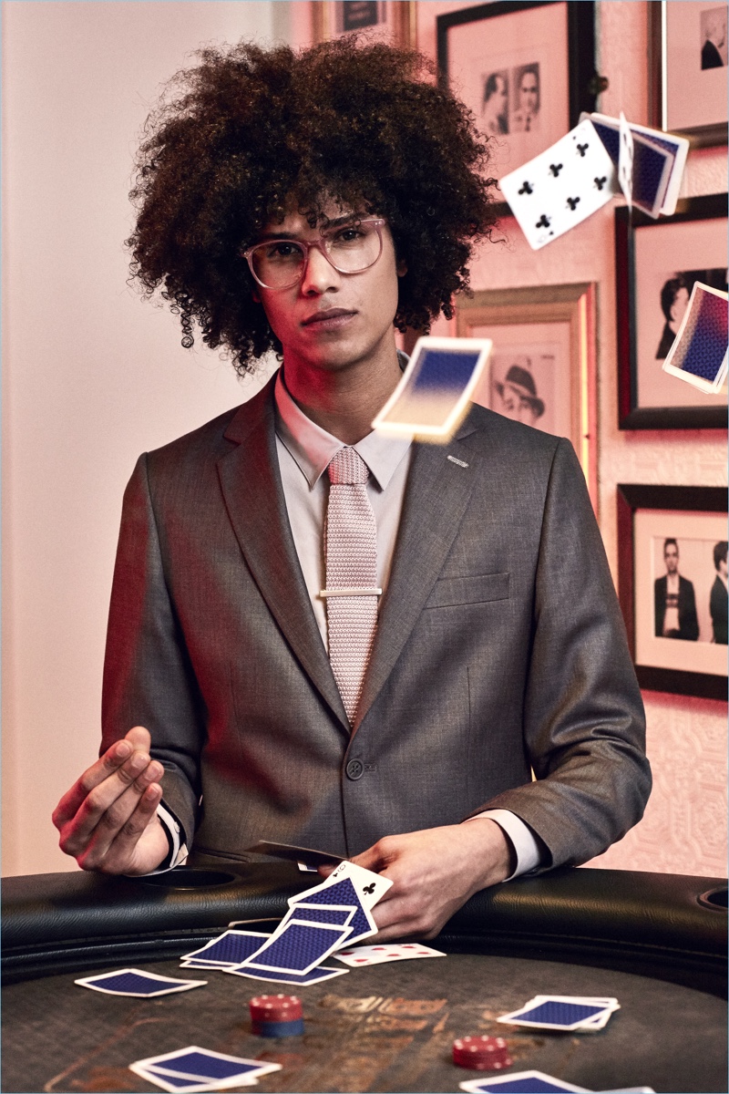 Playing with a deck of cards, Bruno Fabre wears a grey suit by boohooMAN Tailoring.