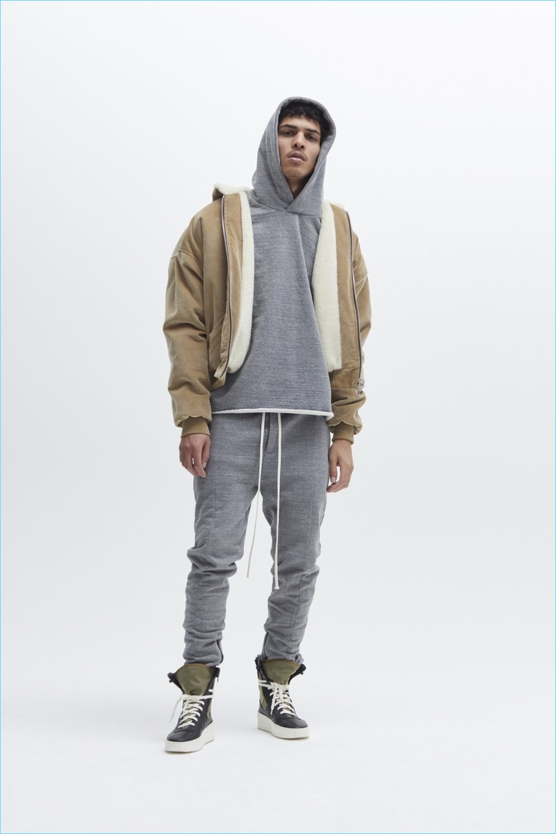 Front and center, Geron McKinley models a grey hoodie, joggers, and a hooded jacket by Fear of God.