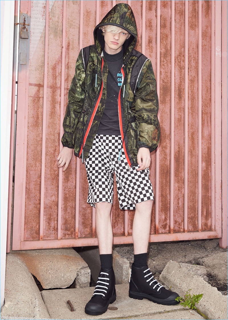 Mixing prints, Turner Barbur rocks a printed lightweight jacket by Givenchy. Turner also wears a Satisfy cult moth eaten sleeveless tee with Givenchy checkerboard prints shorts. The model's look is finished with Givenchy canvas star sneaker boots.