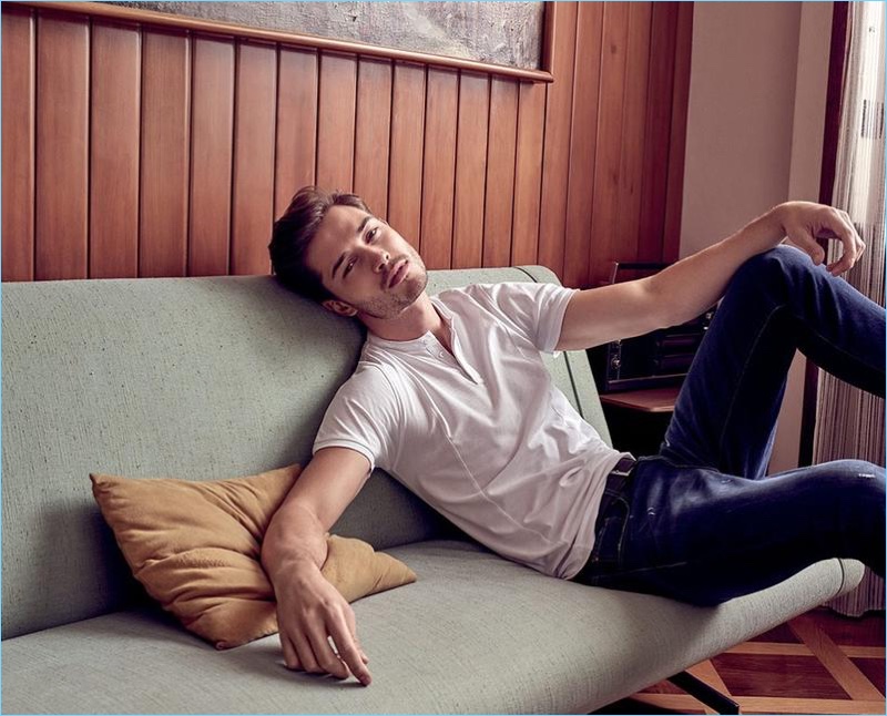 Relaxing on the couch, Francisco Lachowski sports a short-sleeve henley with denim jeans.
