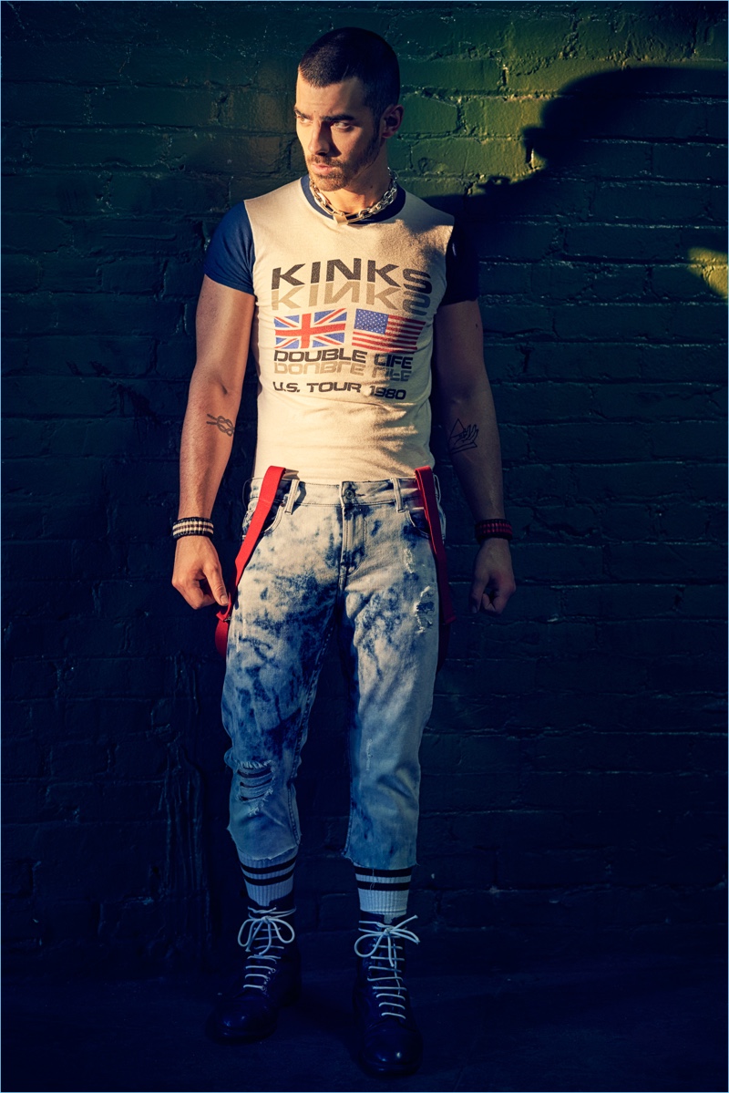 Tapping into a skinhead aesthetic, Joe Jonas rocks a vintage Kinks muscle tee with GUESS jeans. Jonas also wears vintage boots and suspenders with Coach 1941 wristbands.