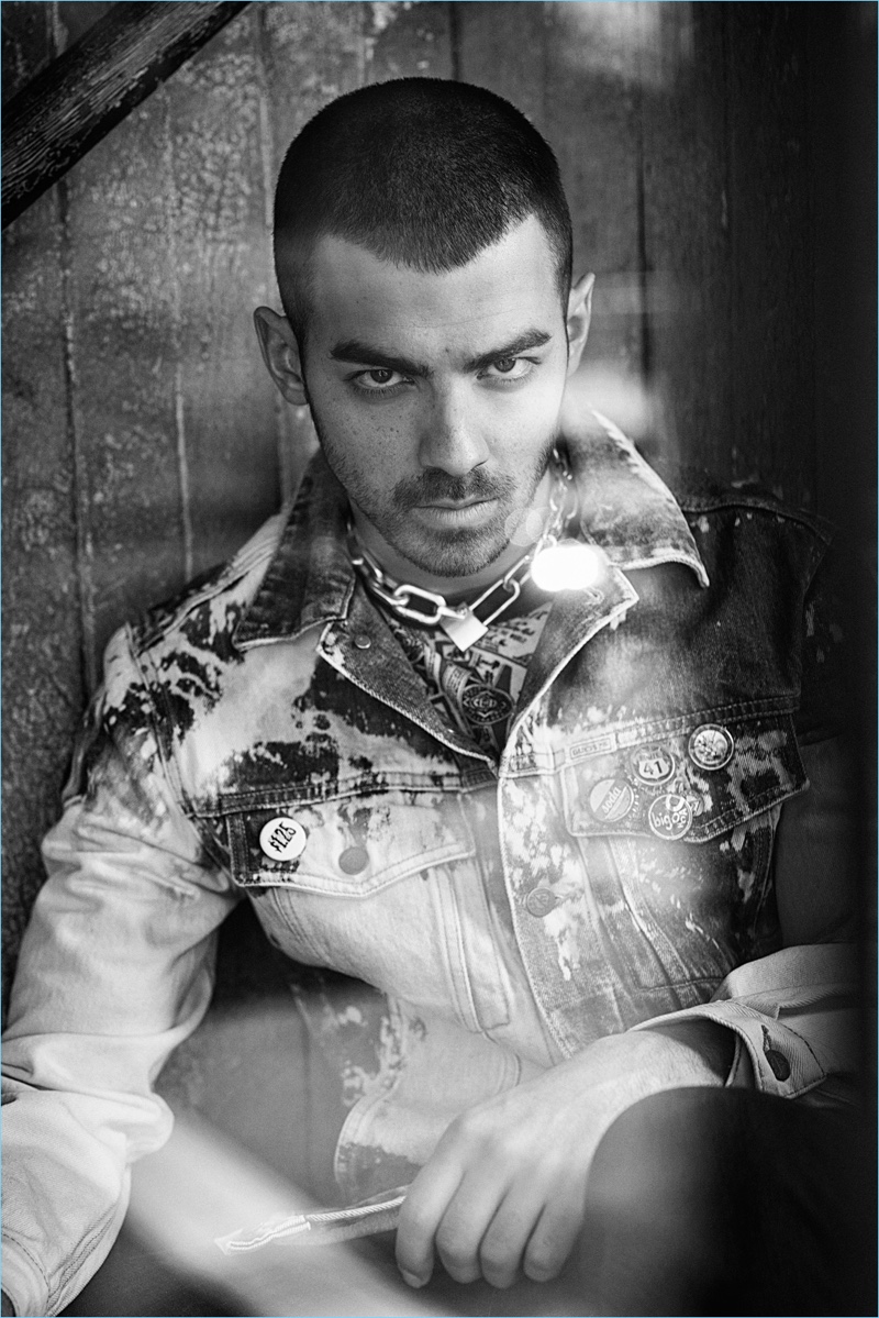 Ready for his closeup, Joe Jonas rocks a vintage GUESS denim jacket with a graphic tee. The singer accessorizes with a Sacai necklace and bottle cap pins by Coach 1941.