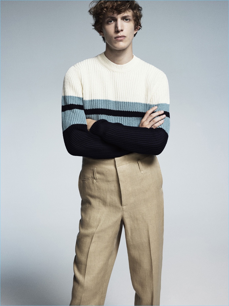 Standing tall, Xavier Buestel wears a color blocked sweater and high waisted trousers by Lardini.