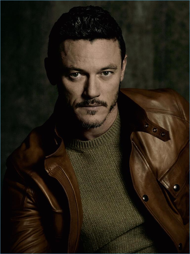 Ready for his close-up, Luke Evans dons a crewneck sweater and brown leather jacket by Ralph Lauren Purple Label.