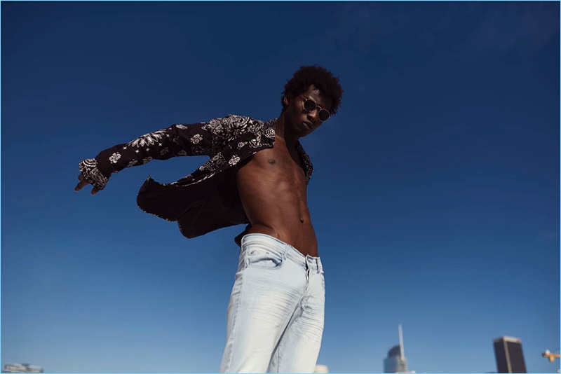 Model Adonis Bosso sports a printed shirt and light wash denim jeans from Other UK.