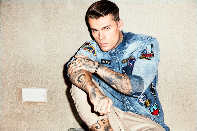 Wearing denim and chinos, Stephen James is pictured in a patch adorned Replay shirt.