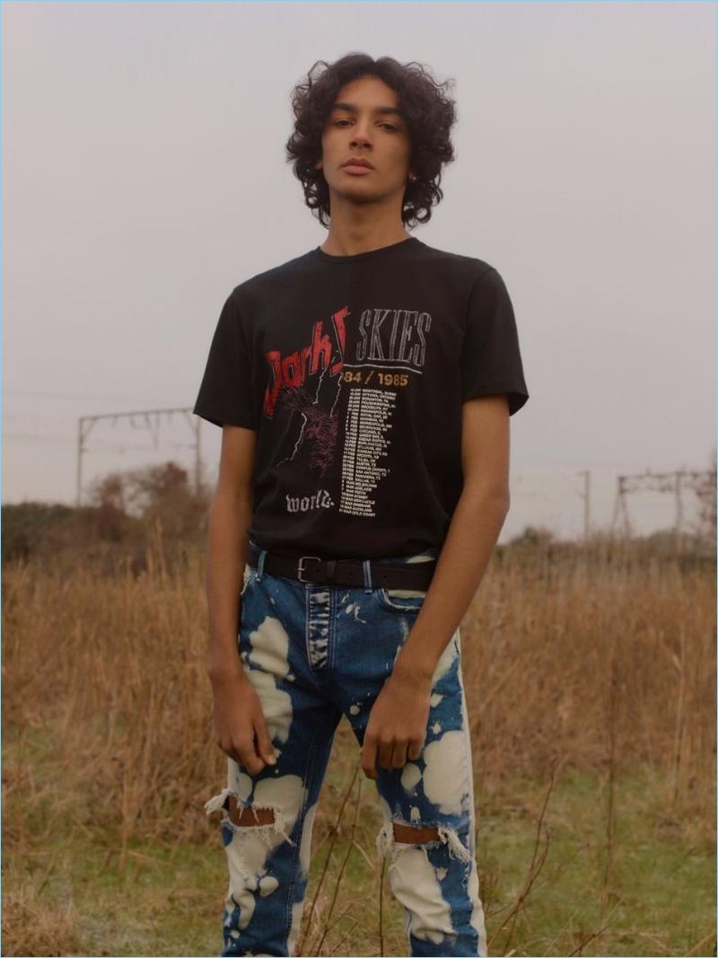 Callum Stoddart wears a washed black spliced band t-shirt and indigo bleach splat ripped stretch skinny jeans from Topman.