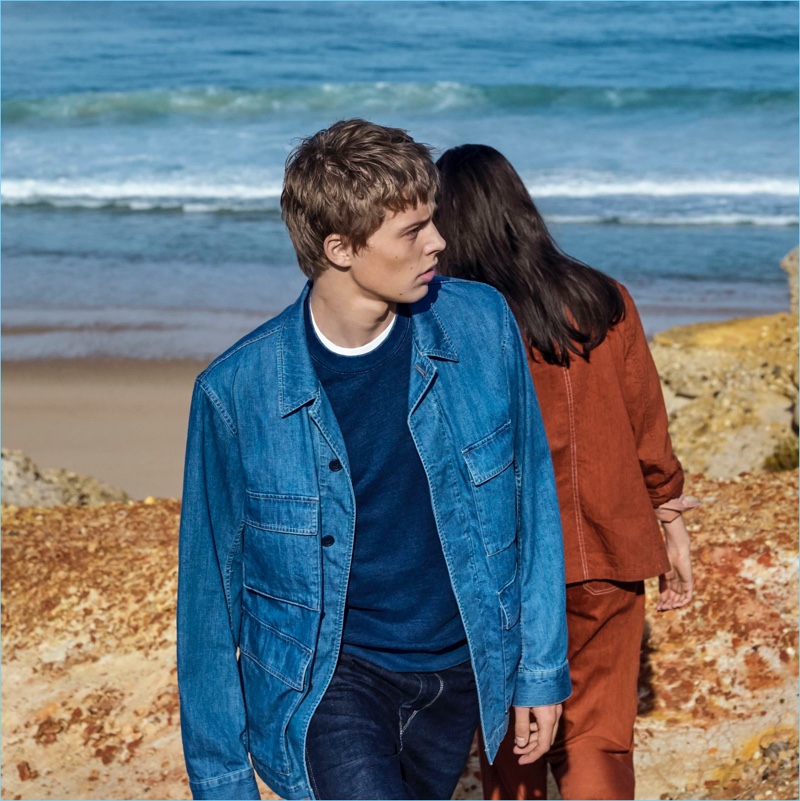 Make a casual blue statement in Uniqlo U's work jacket, crewneck sweater, and denim jeans.