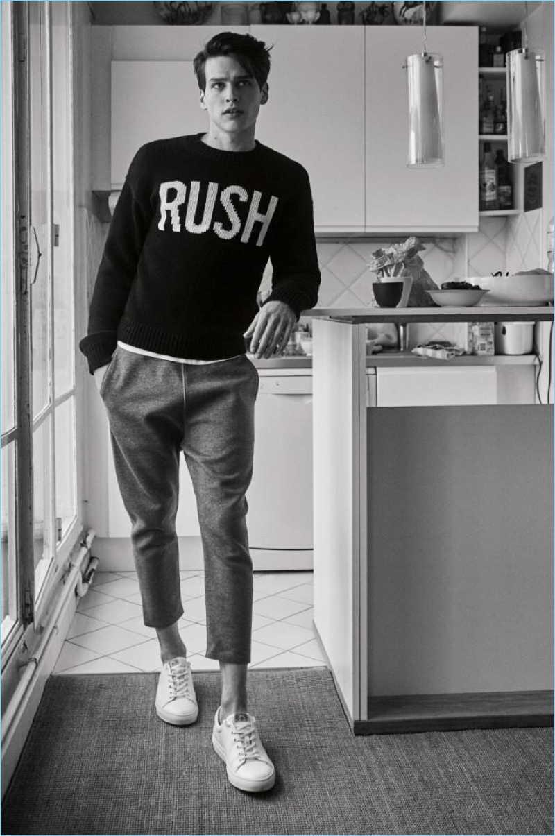 Appearing in a black and white photo, Simon van Meervenne wears a 'RUSH' sweater with cropped trousers by Zadig & Voltaire.