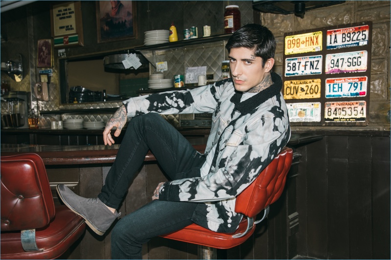 Relaxing at a diner, Daniel Bamdad sports a bleached jacket with distressed jeans and chukka boots from boohooMAN.