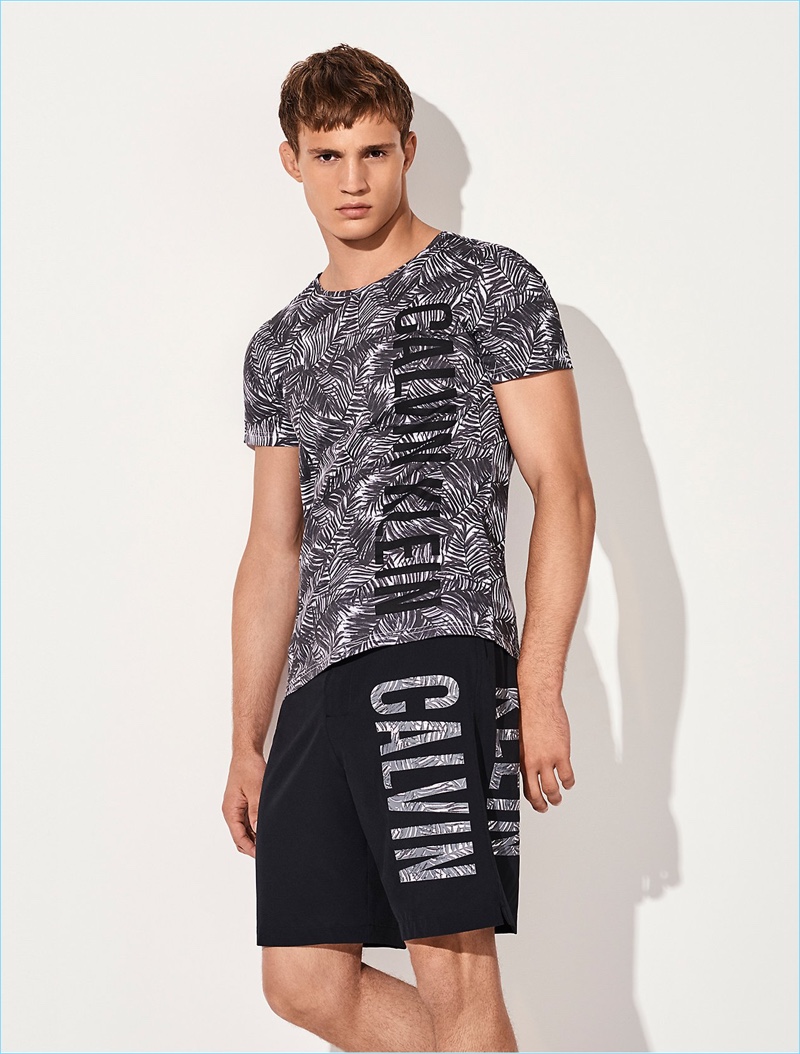 Julian Schneyder reunites with Calvin Klein, wearing its printed logo board shorts $70 and an Intense Power cotton jungle print t-shirt $45.