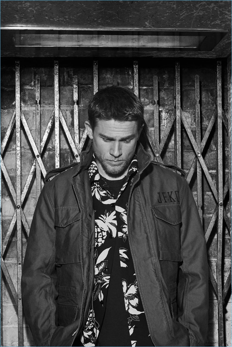 Posing for a black and white photo, Charlie Hunnam wears a Wacko Maria M-65 cotton-canvas field jacket $730. Hunnam also rocks a Saint Laurent camp-collar floral print shirt $750 and a Kapital distressed cotton-jersey t-shirt $185.