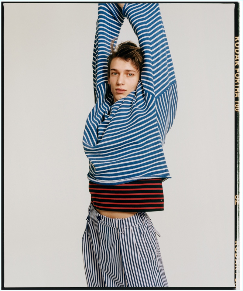 Christopher Einla wears a striped AG t-shirt with a Gosha Rubchinskiy sweater, and Moncler shorts.
