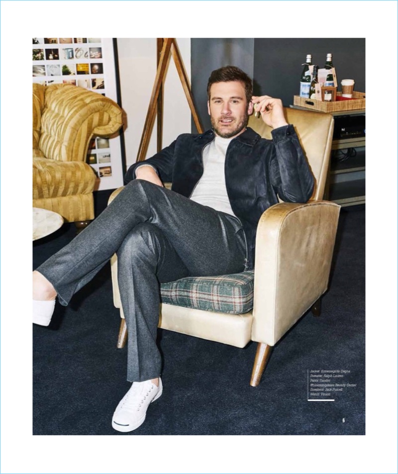 Relaxing, Clive Standen wears an Ermenegildo Zegna jacket with a Ralph Lauren sweater, Sandro trousers, and Jack Purcell sneakers.