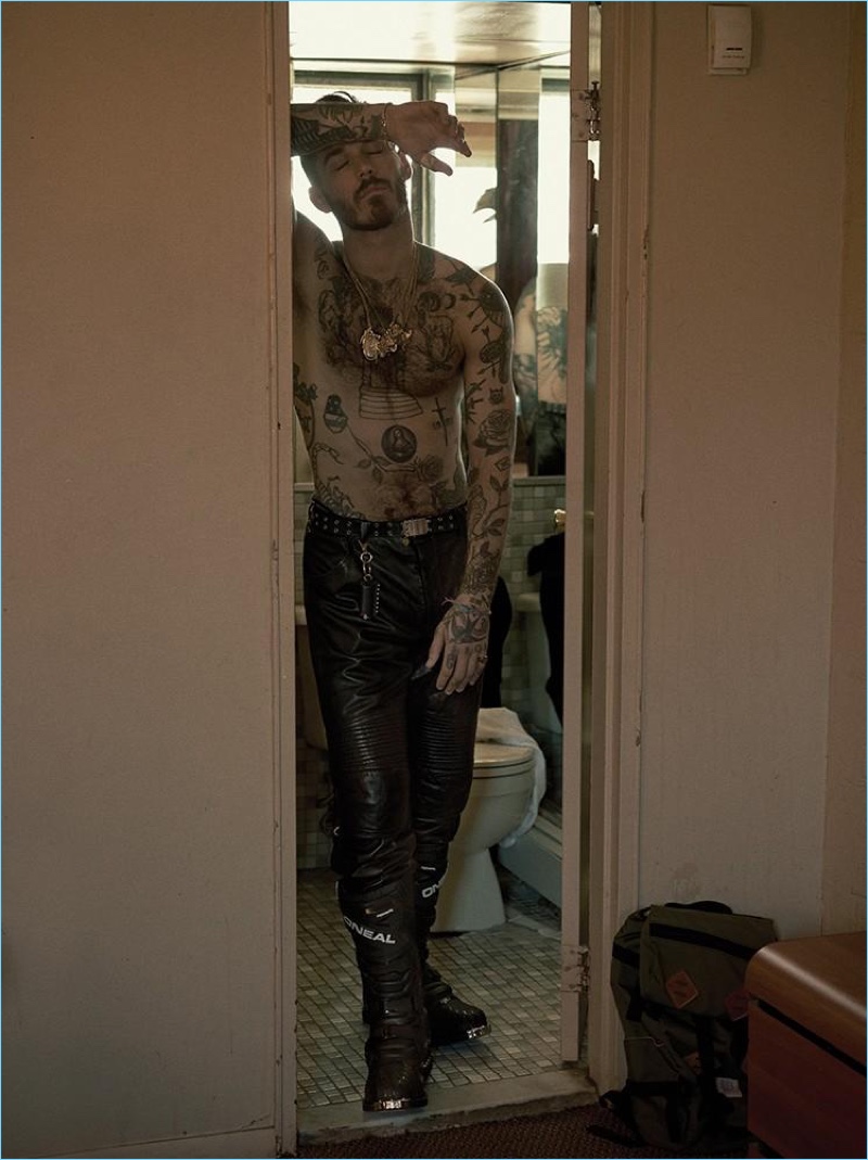 A shirtless David Alexander Flinn shows off his tattoos. The model sports Helmut Lang leather pants with O'Neal boots.