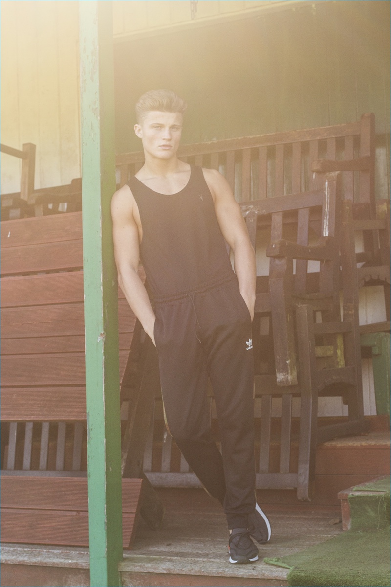 Zach wears tank AllSaints, tracksuit pants Adidas Originals, and sneakers Zara.